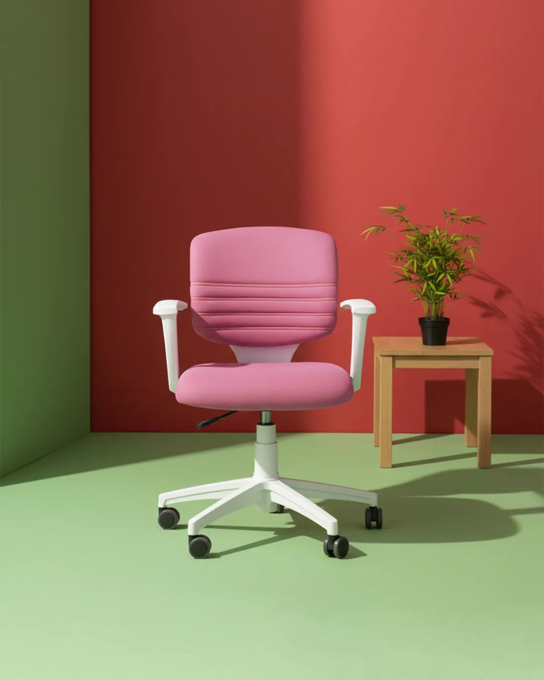 Pink office chair with white base in a room with green floor and red wall.